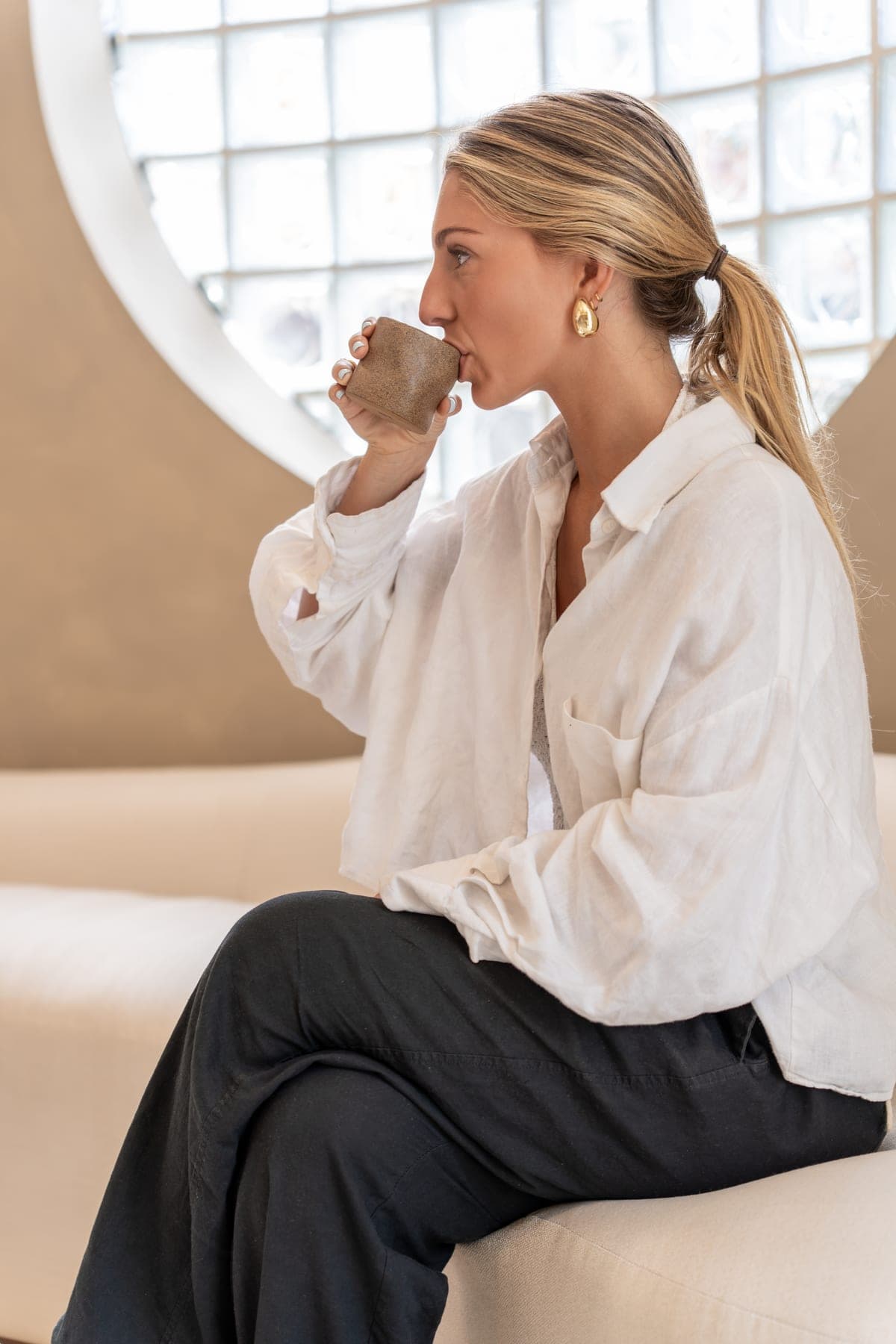 A quiet moment at GLAZE — a guest with a warm drink by the glass-block window